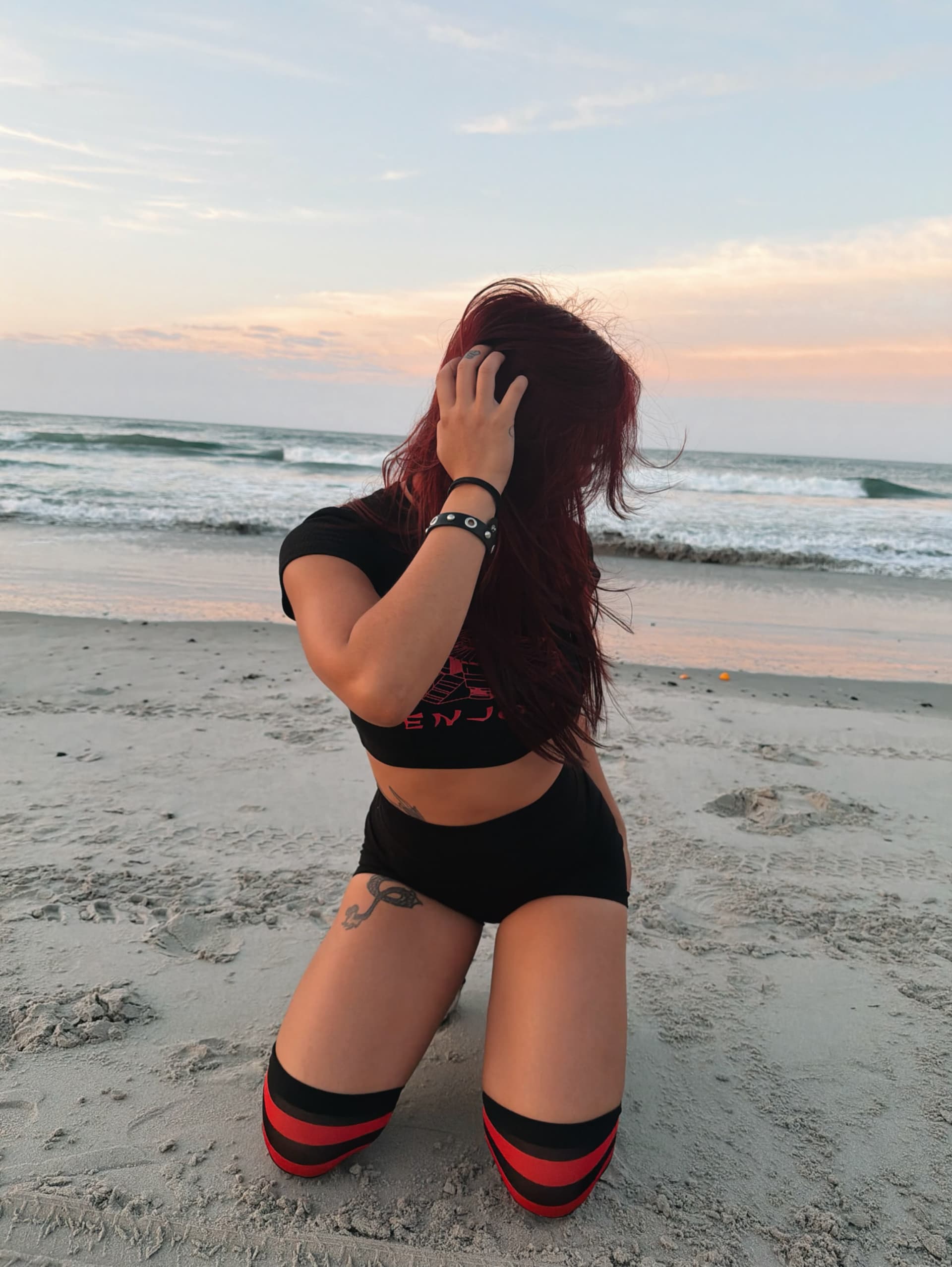 Lyla smiling on the beach at sunset, red hair down